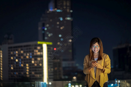 金融的使用智能手机亚洲女商人在泰国Bangkok河边金融区地使用带微笑动作的智能移电话具有职业概念的技术在Technologyw图片