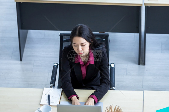 快乐的绝望年轻亚洲商业女在工作场所用办公室工作人员笔记本电脑工作时对办公室后面的工作同事感到不满意的心理压力这些精神与办公室工作图片