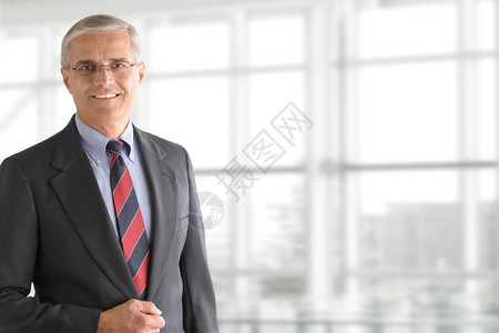 现代的一位成熟商人肖像站在一个巨大的现代办公窗户前他笑着把左侧放出房间找复制品在左边快乐的领导者图片