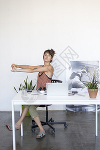 音乐愉快电脑女商人坐在办公室桌旁伸手拉法费尔南德斯图片