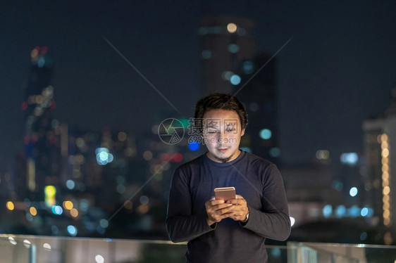 亚洲创意自由职业者使用智能手机在泰国Bangkok河边金融区采取微笑行动技术与职业概念利用智能手机城市商人投资图片