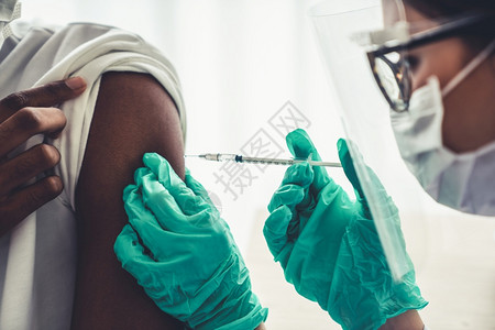 医生给男患者手臂注射疫苗特写图片