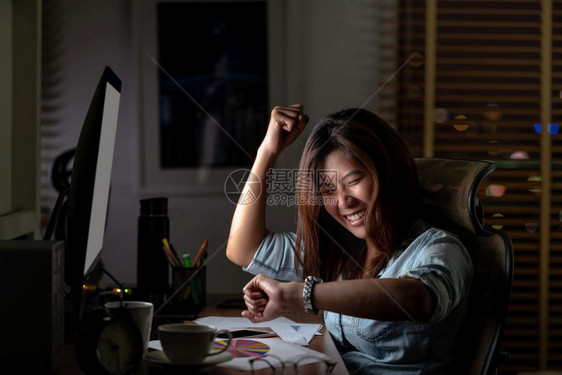 亚洲女商人的肖像她坐在桌上辛勤地工作与幸福行动晚些时在工作场所计算机桌面前摆着电脑努力工作与为时太晚的概念桌子忙碌难图片
