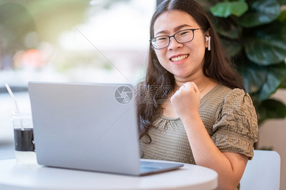忙碌的穿着无线耳机女商人表示自信敢于用笔记本电脑像背景一样坐在咖啡店里工作Asian自由职业者的成功经营十分Speareedco图片