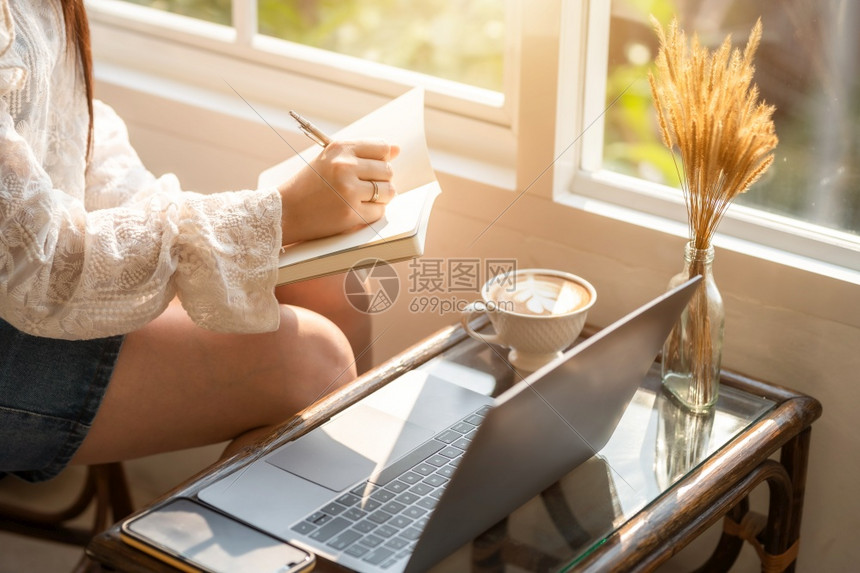 沟通在线的商业女人用笔记本电脑和咖啡杯及智能手机在咖啡店商业生活方式做零用笔记的散工在网吧行政人员图片