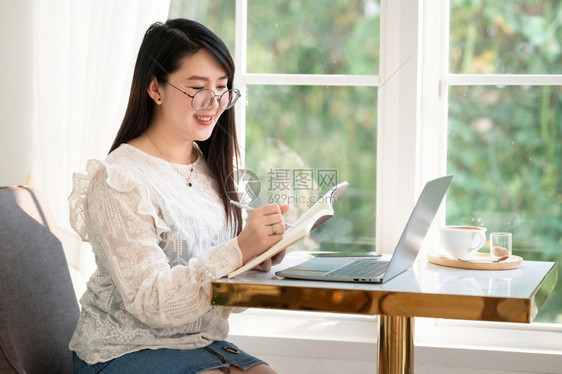 无线的数字作家商业女人用笔记本电脑和咖啡杯及智能手机在咖啡店商业生活方式做零用笔记的散工在网吧图片