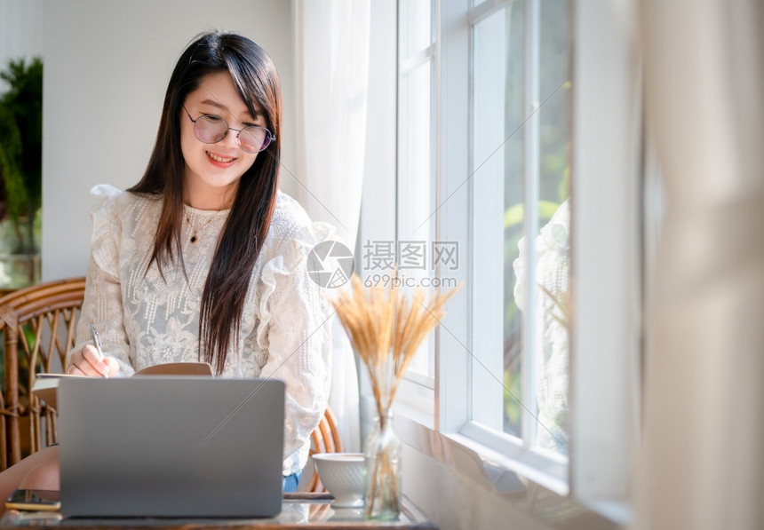 商业女人用笔记本电脑和咖啡杯及智能手机在咖啡店商业生活方式做零用笔记的散工在网吧美丽的沟通女士图片