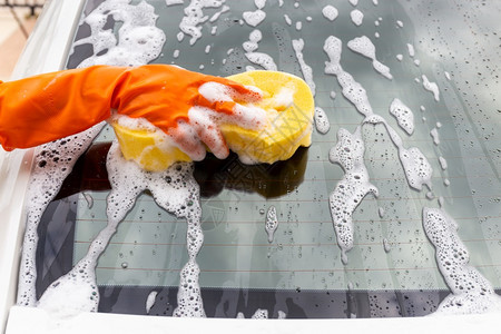 合金人们店铺妇女手戴橙色套背着黄海绵洗后镜的现代汽车或清洁洗概念图片
