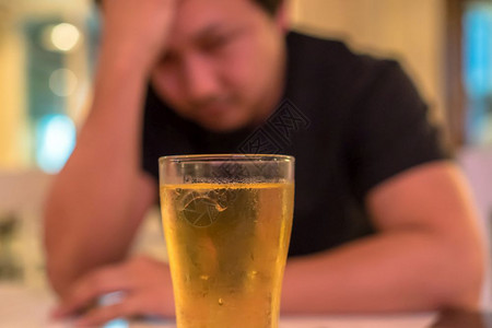 男人孤单亚洲青年男子在孤独和沮丧的行动中手握着头在酒吧和餐馆看到