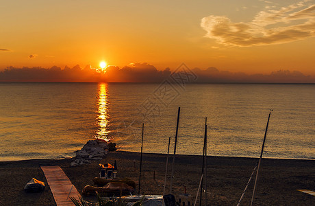 目的地旅游黎明时清晨平静的海面与一个有船的岩石海滩航行图片