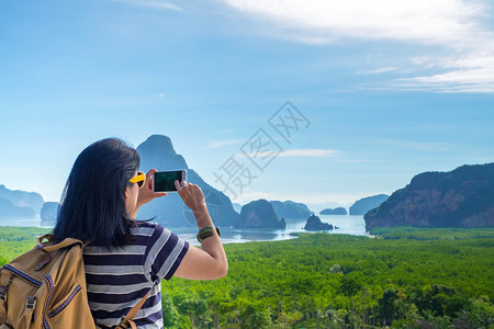 使用手机的年轻旅行女背包员在山顶观赏日出时拍下一张美丽的日出景照片自由漫游者概念KhaoSamedNangCheePhangNg图片