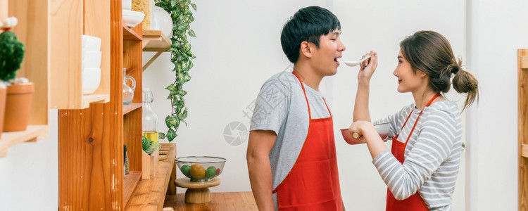 在现代房子夫妻和生活方式厨房和食物概念的厨房做饭时以幸福为行动烹饪的一对情侣或夫妇爱屋内部的图片