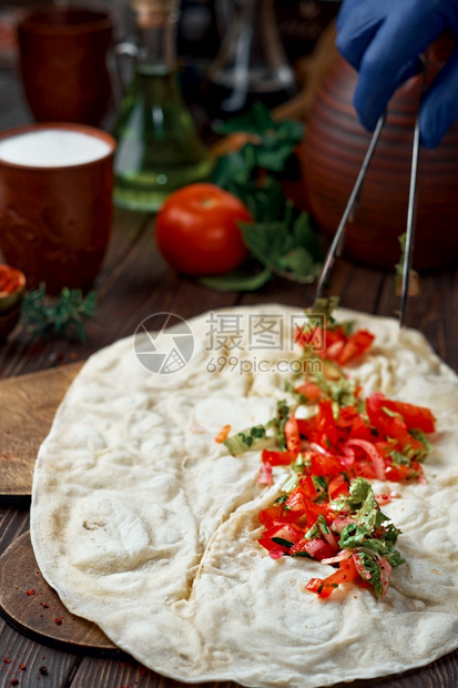 场地由厨师传统土耳其语或阿拉伯东方烤肉卷制作Adanakebabdurumkibab的过程配有沙拉和香料Wooden背景以浅深的图片