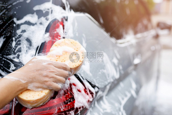 持有手黄色海绵和泡沫清洗窗的工人男子手持黄海绵和泡沫洗车用擦玻璃窗户洗涤剂抓住蓝色的图片