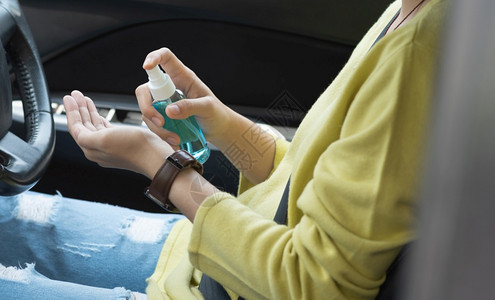 使用酒精喷雾洗涤和手以防止Covid19或Corona的绿衬衫亚洲妇女驾驶汽车前用防毒剂腐卫生保健亚洲人申请车辆图片