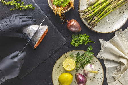 黑石板上的块切削板上的鲑鱼环绕着草药洋葱大蒜树脂虾瓷铁板中的黑混凝土桌面厨房产品木制的图片