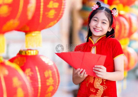 亚洲身着青山传统红衣装饰的亚裔女孩手握红色信封和灯笼上面写着中文字祝福是新年的分肖像问候图片