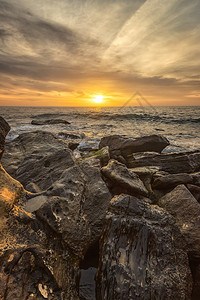 海浪早晨黑色的保加利亚瓦尔纳附近黑海岸的岩石之间闪亮海日出触目惊心图片