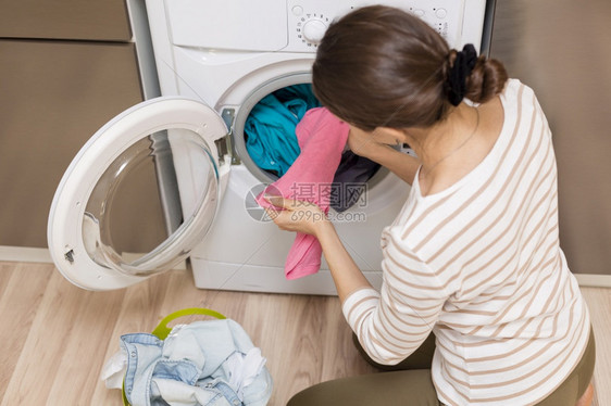 高分辨光相照的女士将衣服取出洗机高品质照片在家工作器具护理图片