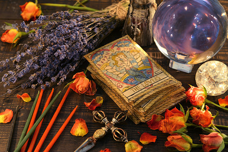 阅读哥特塔罗牌配有魔法水晶球蜡烛和熏衣草花维卡埃萨托里克占卜和神秘背景带有古老的神奇物品用于秘仪式预言图片