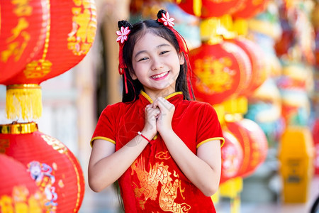 微笑假期小可爱亚洲女孩穿着传统的青相红纸灯上面写着中文字母上帝保佑是财富祝福的赞美中华新年奖章幸运之福美丽的图片