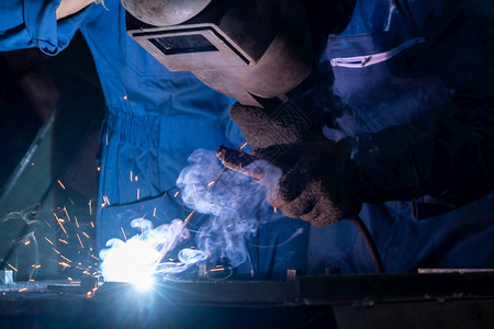 运动头盔铁熟练的金属工人在厂使用弧焊机同时佩戴安全设备金属制品造和建筑维护服务通过手工技能劳动概念熟练的金属工人在厂使用弧焊机图片