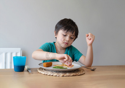 健康的幼儿园7岁男孩的肖像在家吃周日晚饭时有自制鱼手指和薯条一个快乐的孩子吃午餐儿童热菜和新鲜食品健康生活方式概念以及英国的图片