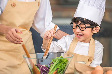 在室内爱做饭的亚洲小可爱男孩在家庭厨房里和妈一起做饭很滑稽人们的生活方式和家庭自制食物原料概念两个泰国人制作了由水生食物沙拉酮可图片