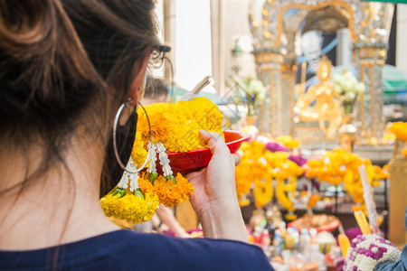 一名妇女用泰国曼谷Erawan神社的花草园做礼仪祭式户外愿望图片