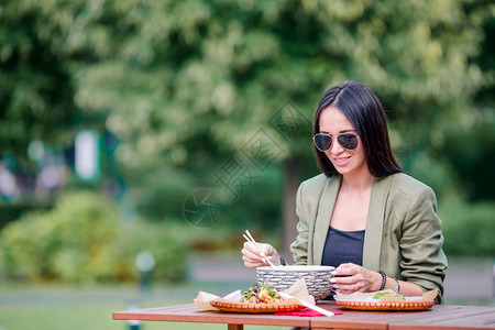 在户外咖啡厅吃亚洲街边食物的年轻美女吃饭的年轻子在街上抢走面条旅游白种人烹饪图片