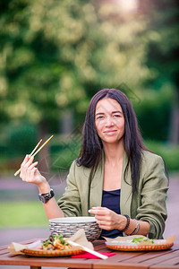 厨师城市镇在户外咖啡厅吃亚洲街边食物的年轻美女吃饭的年轻子在街上抢走面条图片