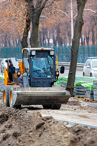 沿着在下面紧压路平层的沙土在沿垂直图象公路铺筑的泥板前先于即将到来的砂土复制空间A紧压平面层在建筑工地垂直图象施中沿人行道移动工图片