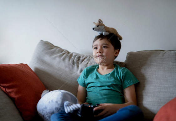 新的放松在家玩网上游戏年轻男孩坐在沙发上玩具乐周末放轻松新生活方式与相伴后的习惯笑声iwhitbox技术图片