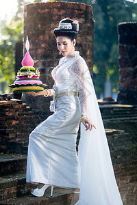 原来的身着泰国白色传统服装穿着Krathoong和坐在泰国古老城市塔寺门前的Trathong妇女LoyKrathong节Tran图片