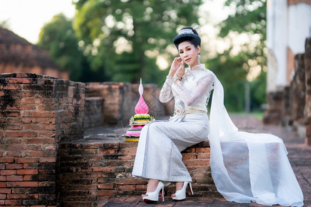 传统的身着泰国白色传统服装穿着Krathoong和坐在泰国古老城市塔寺门前的Trathong妇女LoyKrathong节Tran图片
