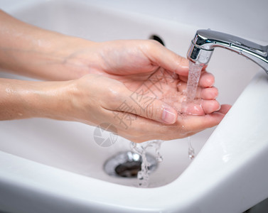在浴室用自来水洗手的妇女在浴室用自来水在槽下清洗龙头以保持个人卫生第一步骤是清洁脏手以防止流感和冠状程序湿的为了图片