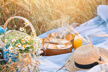 新鲜的在小麦田吉他草帽带眼镜的葡萄酒和一篮子雏菊中在小麦田里举行关于自然的野餐收成放松图片