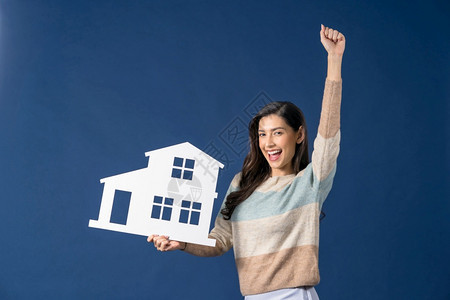 快乐的年轻微笑亚洲女持有和展示白彩屋模拟论文关于蓝色背景投资销售和保险建筑财产概念的思维出售和保险建筑财产概念保持成功图片