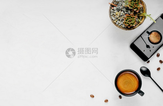 杯子摄影立即的一杯含泡沫热咖啡杯放在广白背景上并有复制空间平铺黑杯休息智能手机和背面花朵的加罗克酒图片