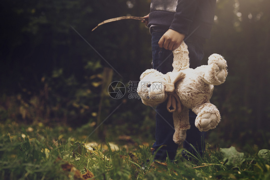 在森林中独自守着Tedddy醒来的TedTed受难儿童失落或无家可归概念的男孩孤单持有其泰德受宠坏儿童失踪或无家可归的概念悲哀科图片