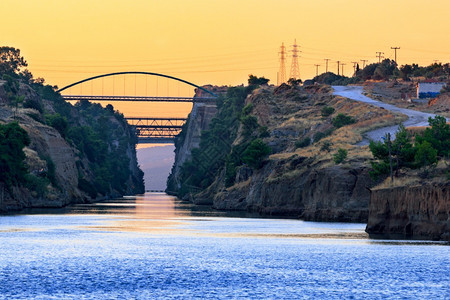 陡悬崖在两海之间运输科林斯河的罗基水走廊在太阳升起和清晨烟雾空间的光线下看到运河上的桥梁清晨在希腊两海之间的Corinth运河输图片
