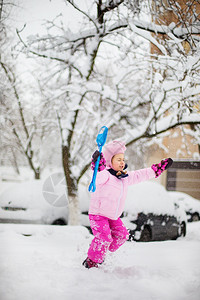 孩子在冬天玩雪一个穿着亮色夹克和针织帽的小女孩在冬季公园里为圣诞节捕捉雪花孩子们在白雪覆盖的花园里玩耍和跳跃一个小女孩在明亮的夹图片