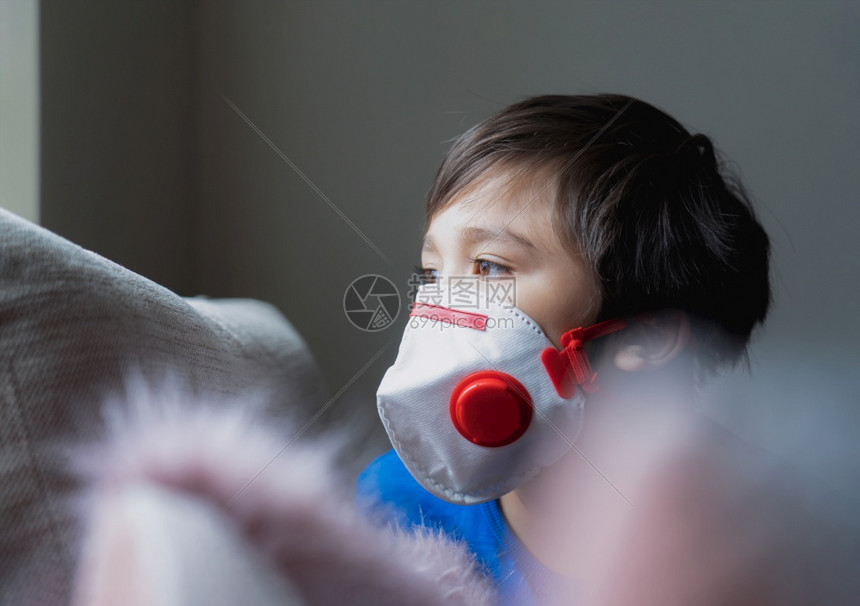 试过了身戴医疗面罩脸朝窗外望着胸部咳嗽的以保护下午25时孤独面伤悲的男孩在家呆着以获得共同生活流感和疾病保护形式污染锁图片