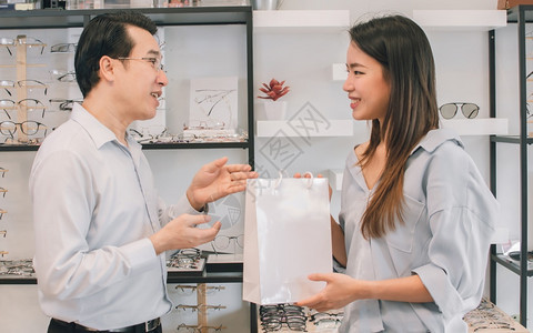 销售量配镜师亚洲美丽的女客户从省销售折扣和促概念部的一位男子那里购买眼镜这些顾客是亚洲美丽的女客户诊断图片