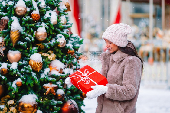 常绿在雪地户外的中拥有圣诞礼物的漂亮女人在一个美妙的冬天节日快乐女孩在雪中的firtree树枝附近新年分支冷杉图片