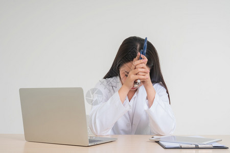 强调年轻的亚洲女医生坐在办公桌旁由于过度工作精神压力疲劳的概念和医生责任她看起来不快乐和疲倦处理沮丧的病情郁闷休息图片
