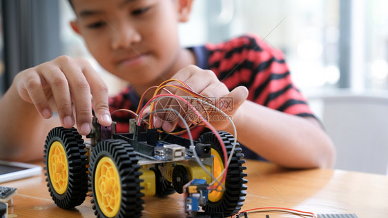 手工制作的汽车模型工作电子集中男孩在实验室制造机器人的建筑工程早期开发暗展创新现代技术概念和新颖教育电子的图片