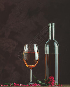 饮料瓶装玫瑰酒和玻璃配有玫瑰酒和花瓣深底背景的粉红玫瑰Beautiul情人节或结婚贺卡活力庆典图片