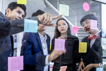 成功快乐的工人团体由不同别的亚洲商人组成群体男女双和变者并使用它注意到的文章分享想法集思广益的概念在办公室会议的玻璃墙上颜色合作图片