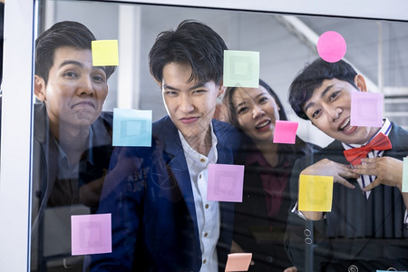 战略成功快乐的工人团体由不同别的亚洲商人组成群体男女双和变者并使用它注意到的文章分享想法集思广益的概念在办公室会议的玻璃墙上设计背景